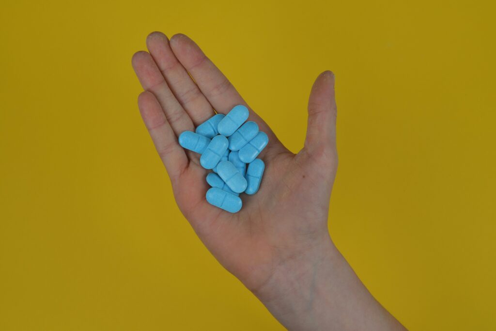 Eine Hand voll blauer Pillen Alpha Liponsäure.